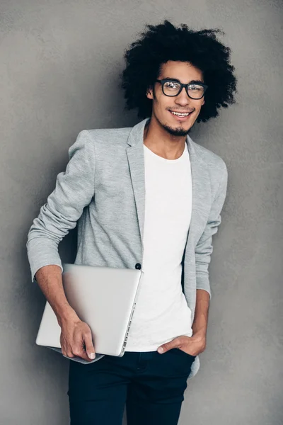 Африканский мужчина держит ноутбук и смотрит — стоковое фото