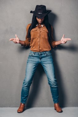 Şapkalı Afrikalı kadın el silahlarını gesturing ve gri arka plan karşı dururken aşağı bakıyor