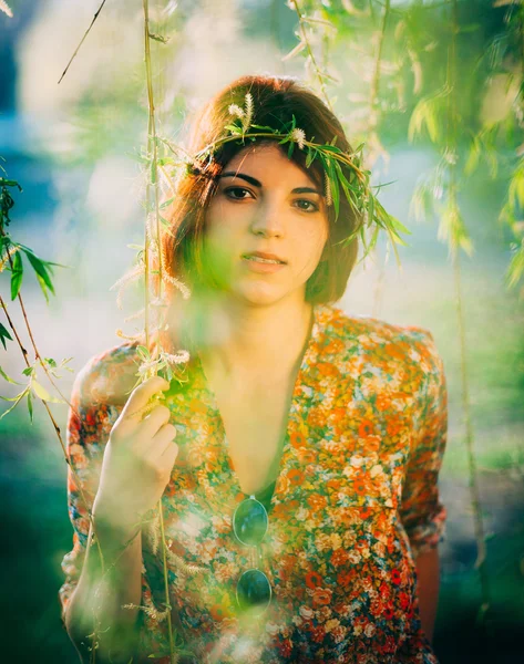 Adorável jovem com uma coroa de flores, no parque — Fotografia de Stock