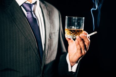 Bir bardak viski ve sigara ile takım elbiseli adam