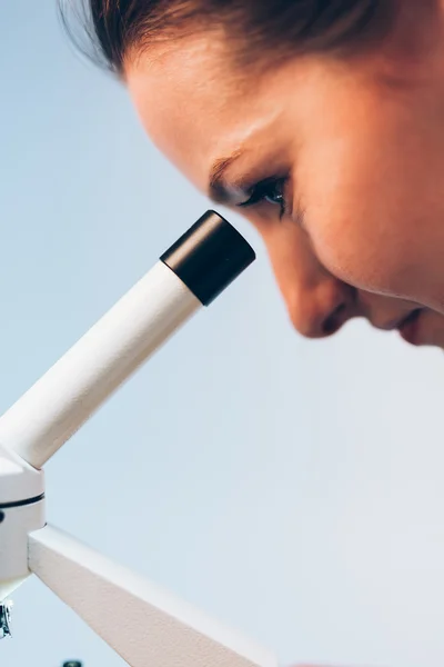Kvinna som tittar genom Mikroskop — Stockfoto