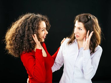 Güzel genç kızlar siyah bir arka planda surat asıp eğleniyorlar.