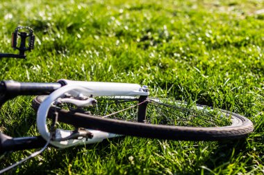 Güneşli bir günde çimlerin üzerinde yatarken bir bisiklet tekerleğinin yakın çekimi 