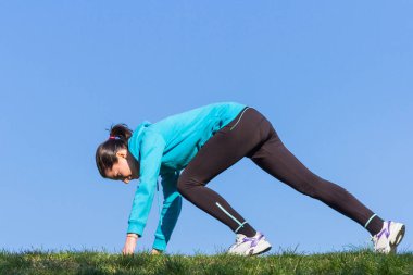 Genç bir kadın güneşli bir günde dışarıda geriniyor.