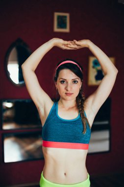 Ciddi bir kadın pozu. Kasları kaslı, el ele tutuşmuş, başının üstünde.