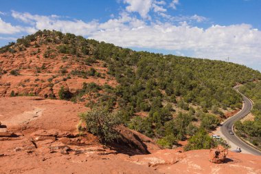 Kızıl kaya oluşumları ve dağların arasından geçen bir yol.