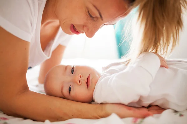 Mutter hält Baby auf Bett — Stockfoto