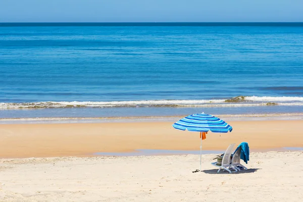 Sluneční lehátka a slunečník na pláži — Stock fotografie