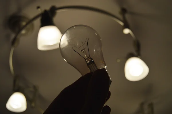 Light Bulb Held Person Hand Silhouetted Bright Track Light — Stock Photo, Image