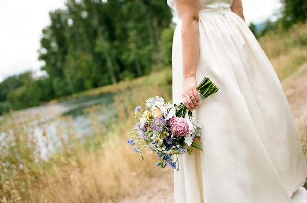 Braut hält Blumenstrauß am Hochzeitstag — Stockfoto