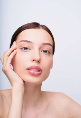 Dikey çekim, yakın plan, seksi beyaz kız Langucor kameraya bakıyor, sağ eliyle yüzüne dokunuyor, dudakları aralık, genç ve güzel. Yüz için kozmetik prosedürleri kavramı.