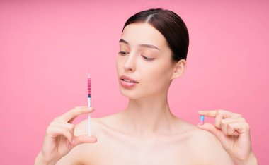 Çıplak omuzlu, siyah saçlı, elinde şırıngayla iğne ve hap tutan çekici ve seksi bir kız güzellik için iğne yaptırmak istiyor. İlaç konsepti, eczacılık..