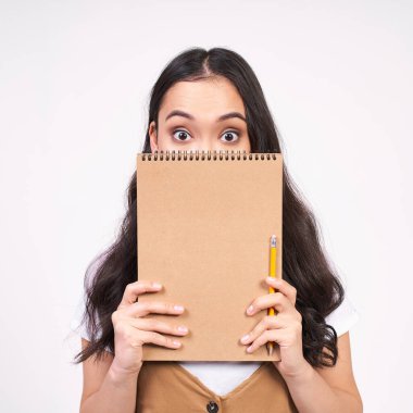 Kahverengi gözlü, siyah saçlı, yüzünün yarısını kahverengi not defteriyle kaplayan, beyaz arka planda poz veren komik, esmer Asyalı kadın. Boşluğu kopyala.