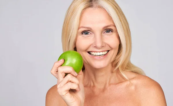 彼女の手にジューシーな緑のリンゴを保持かわいい笑顔ブロンドの年齢の先輩女性 笑顔の健康と美しさの概念 美しさの概念の利点 — ストック写真