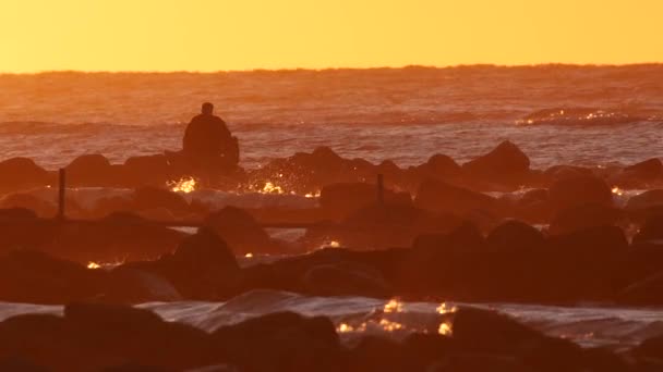 Silhouette eines Mannes, der sich bei Sonnenuntergang am Meer entspannt, Zeitlupe — Stockvideo