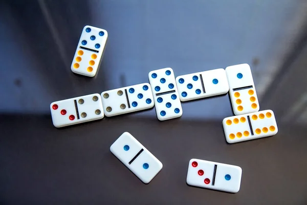 Playing dominoes. White dominoes on dark table. Top view, flat lay.