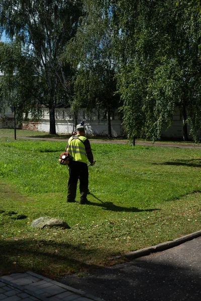 Yazın çim biçme makinesiyle çimleri biçen bir adam.