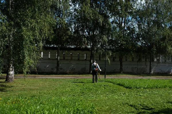 一个人在草坪上用修剪草机割草 — 图库照片
