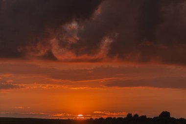 Fırtınadan önce gün batımının arka planında kara bir gök gürültüsü