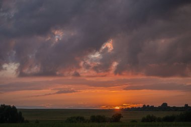 Fırtınadan önce gün batımının arka planında kara bir gök gürültüsü