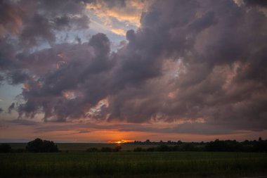Fırtınadan önce gün batımının arka planında kara bir gök gürültüsü