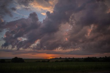 Fırtınadan önce gün batımının arka planında kara bir gök gürültüsü