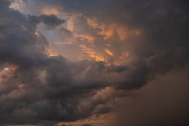 Fırtınadan önce gün batımının arka planında kara bir gök gürültüsü