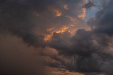 Fırtınadan önce gün batımının arka planında kara bir gök gürültüsü