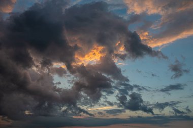 Fırtınadan önce gün batımının arka planında kara bir gök gürültüsü