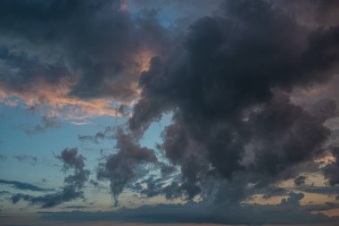Fırtınadan önce gün batımının arka planında kara bir gök gürültüsü