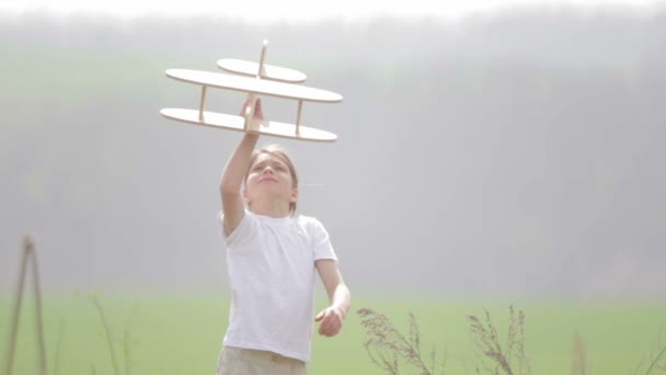 Un garçon caucasien jouant avec un avion modèle. Portrait d'un enfant avec un plan en bois dans un champ. Garçon dans la nature joue avec la disposition de l'avion .