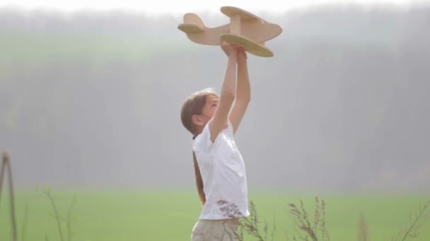 Un garçon caucasien jouant avec un avion modèle. Portrait d'un enfant avec un plan en bois dans un champ. Garçon dans la nature joue avec la disposition de l'avion .