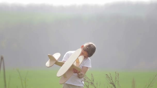 Un garçon caucasien jouant avec un avion modèle. Portrait d'un enfant avec un plan en bois dans un champ. Garçon dans la nature joue avec la disposition de l'avion .