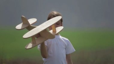 Bir model uçak ile oynayan beyaz çocuk. Bir alan ahşap bir düzlemde bir çocuk portresi. Çocuk doğada uçak düzeni ile çalış.
