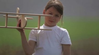 Bir model uçak ile oynayan beyaz çocuk. Bir alan ahşap bir düzlemde bir çocuk portresi. Çocuk doğada uçak düzeni ile çalış.