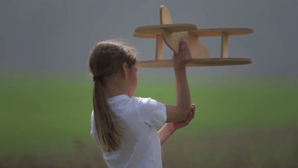 Un garçon caucasien jouant avec un avion modèle. Portrait d'un enfant avec un plan en bois dans un champ. Garçon dans la nature joue avec la disposition de l'avion .