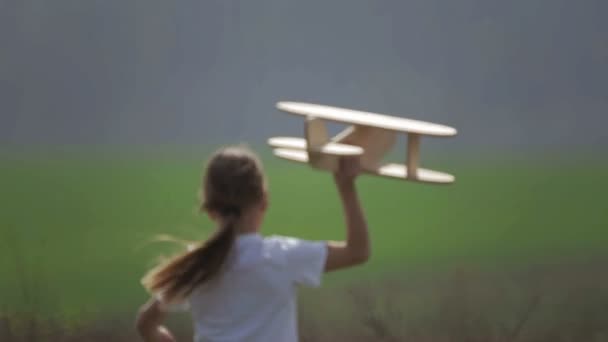 Un garçon caucasien jouant avec un avion modèle. Portrait d'un enfant avec un plan en bois dans un champ. Garçon dans la nature joue avec la disposition de l'avion .