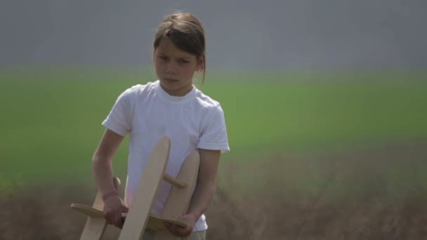 Un garçon caucasien jouant avec un avion modèle. Portrait d'un enfant avec un plan en bois dans un champ. Garçon dans la nature joue avec la disposition de l'avion .