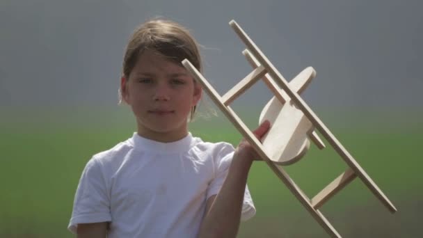 Un garçon caucasien jouant avec un avion modèle. Portrait d'un enfant avec un plan en bois dans un champ. Garçon dans la nature joue avec la disposition de l'avion .
