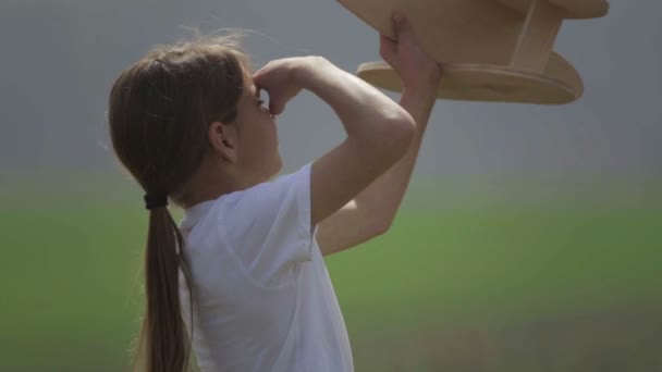 Un garçon caucasien jouant avec un avion modèle. Portrait d'un enfant avec un plan en bois dans un champ. Garçon dans la nature joue avec la disposition de l'avion .