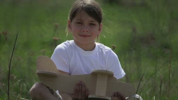 Chico caucásico jugando con un avión modelo. Retrato de un niño con un plano de madera en un campo. Niño en la naturaleza juega con el diseño de la aeronave . — Vídeos de Stock