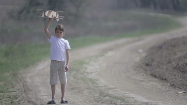 Bir model uçak ile oynayan beyaz çocuk. Bir alan ahşap bir düzlemde bir çocuk portresi. Çocuk doğada uçak düzeni ile çalış. — Stok video
