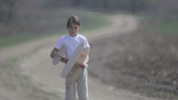 Un garçon caucasien jouant avec un avion modèle. Portrait d'un enfant avec un plan en bois dans un champ. Garçon dans la nature joue avec la disposition de l'avion .