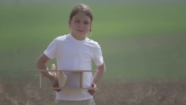 Un garçon caucasien jouant avec un avion modèle. Portrait d'un enfant avec un plan en bois dans un champ. Garçon dans la nature joue avec la disposition de l'avion .