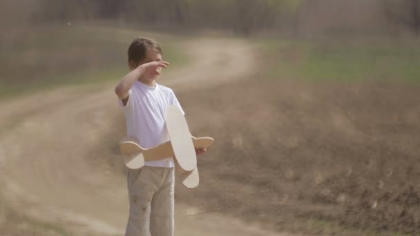 Un garçon caucasien jouant avec un avion modèle. Portrait d'un enfant avec un plan en bois dans un champ. Garçon dans la nature joue avec la disposition de l'avion .
