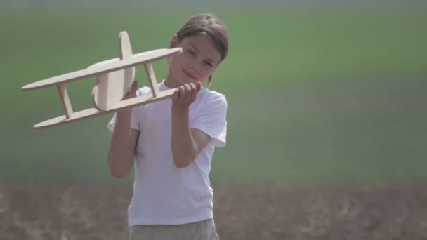 Un garçon caucasien jouant avec un avion modèle. Portrait d'un enfant avec un plan en bois dans un champ. Garçon dans la nature joue avec la disposition de l'avion .