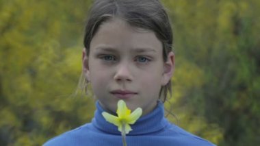 Bahar bir çocuk portre sarı nergis çiçek ile. Kendini beğenmiş çocuk çiçeği nergis kokulu. Çocuğun yüzü genç onun elinde bir çiçek ile.