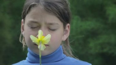 Bahar bir çocuk portre sarı nergis çiçek ile. Kendini beğenmiş çocuk çiçeği nergis kokulu. Çocuğun yüzü genç onun elinde bir çiçek ile.
