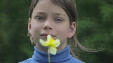 Bahar bir çocuk portre sarı nergis çiçek ile. Kendini beğenmiş çocuk çiçeği nergis kokulu. Çocuğun yüzü genç onun elinde bir çiçek ile.