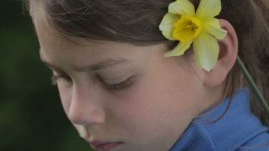 Bahar bir çocuk portre sarı nergis çiçek ile. Kendini beğenmiş çocuk çiçeği nergis kokulu. Çocuğun yüzü genç onun elinde bir çiçek ile.